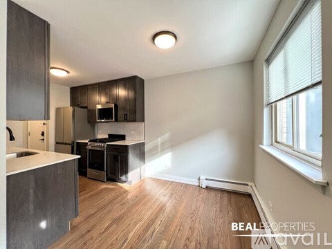 A kitchen with dark wood cabinets and a white countertop is available for rent.