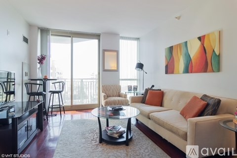 A living room with a beige couch, a glass coffee table, and a painting on the wall.