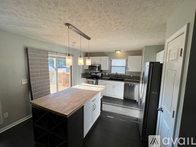 A kitchen with a wooden island and stainless steel appliances.