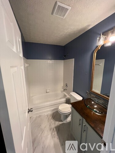 A bathroom with a white toilet, a white bathtub, and a brown countertop.