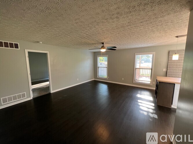 A spacious room with wood flooring and a ceiling fan.