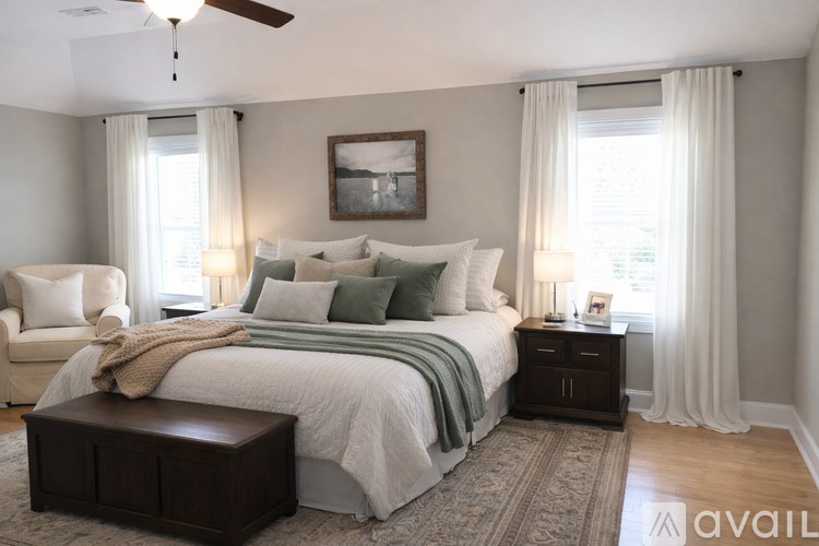 A bedroom with a large bed, a ceiling fan, and a rug on the floor.