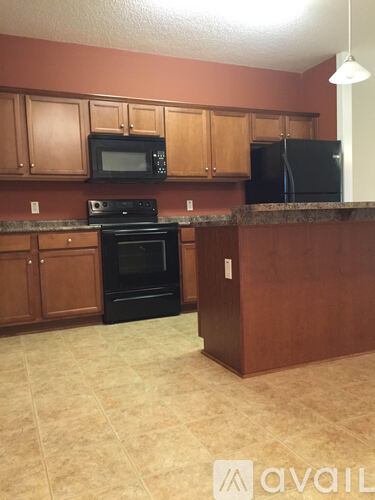 A kitchen with brown cabinets and black appliances.