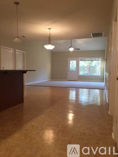 A room with a brown floor and a ceiling fan.