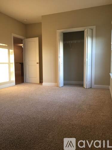 A carpeted room with a door and a window.