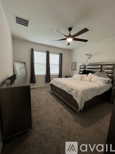 A bedroom with a bed, dresser, and ceiling fan.
