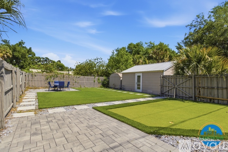 A backyard with a patio, a fence, and a small building.