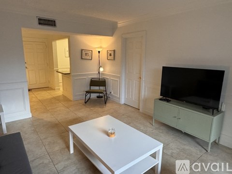 A living room with a white table and a television.