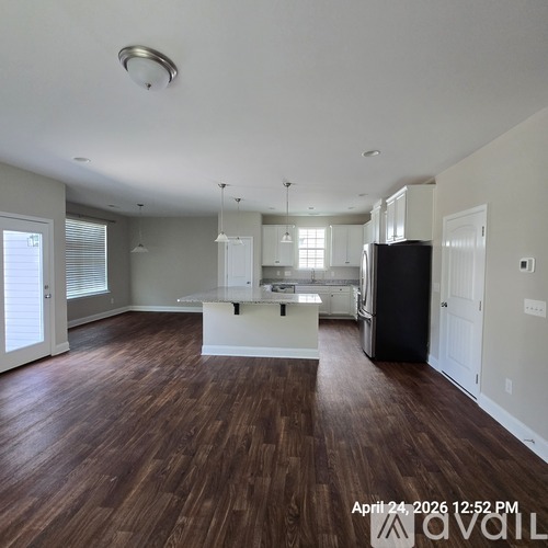 A spacious kitchen with dark wood flooring and white cabinetry.