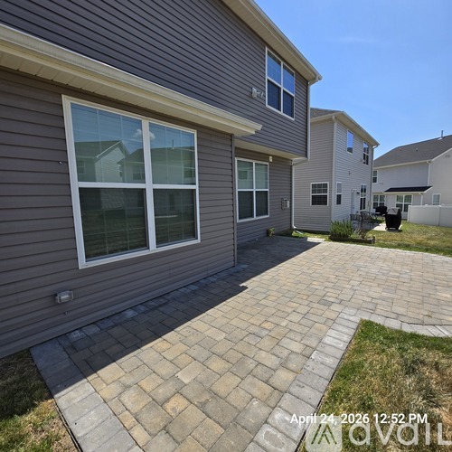 A house with a grey siding and a brick walkway in front.