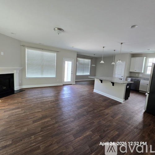 A spacious living room with wood flooring and a fireplace.