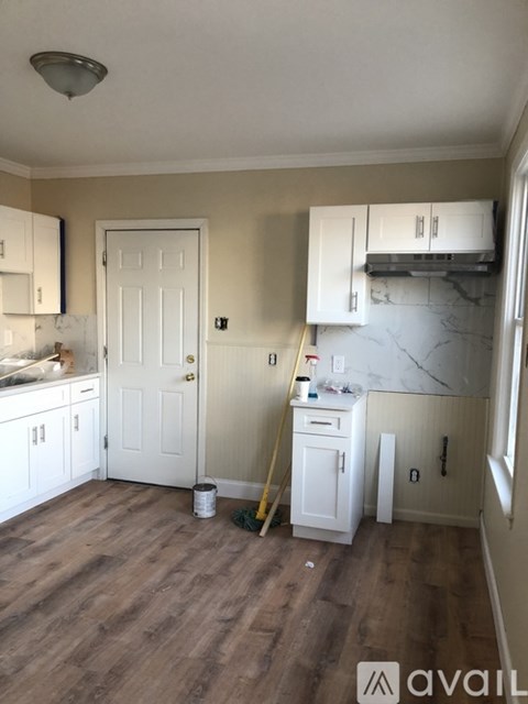 A kitchen with white cabinets and a white door.