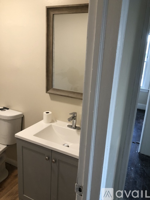 A bathroom with a toilet, sink, and mirror.