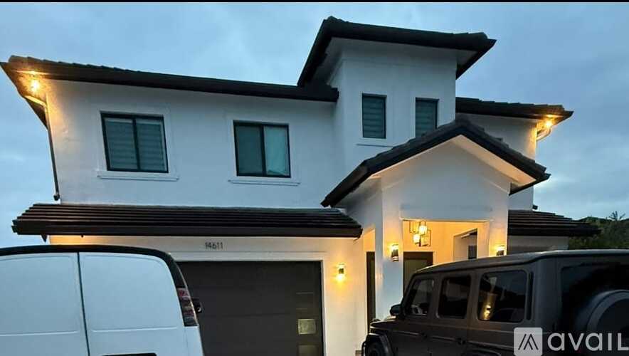 A modern house with a white exterior and a dark roof is shown with a van parked in front.
