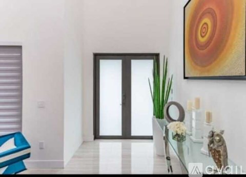 A modern living room with a glass coffee table and a large abstract painting on the wall.