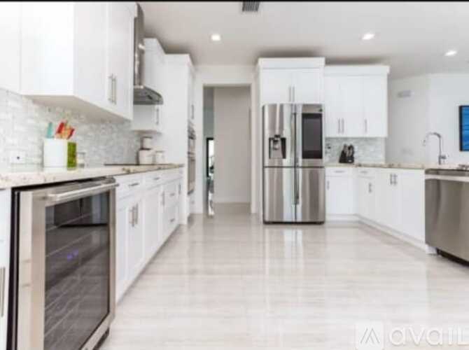 A modern kitchen with white cabinets and stainless steel appliances.