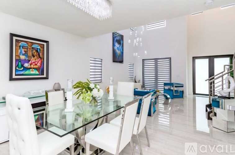 A modern dining room with a glass table and white chairs.