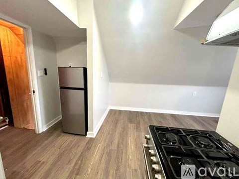 A kitchen with a stove top and a refrigerator.