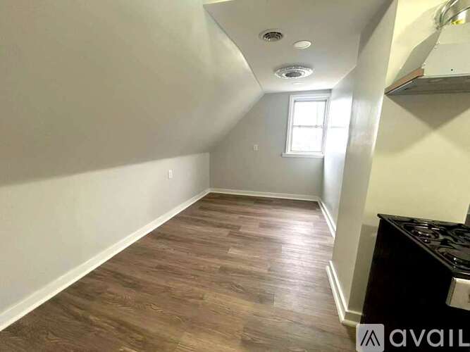 A room with wooden flooring and a window on the right side.