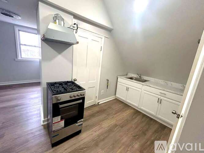 A kitchen with a stove, sink, and cabinets.