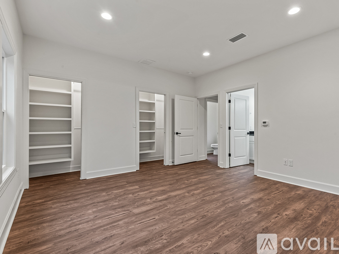 A spacious room with wooden flooring and white walls.