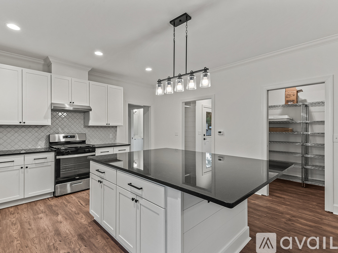 A modern kitchen with white cabinets and a black countertop.