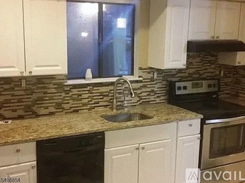 A kitchen with a black oven and a stone backsplash.