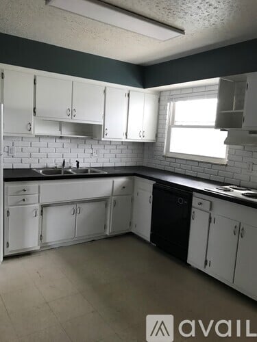 A kitchen with white cabinets and a black countertop.