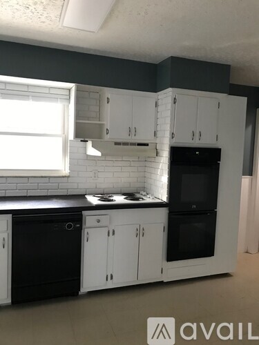 A kitchen with black appliances and white cabinets.