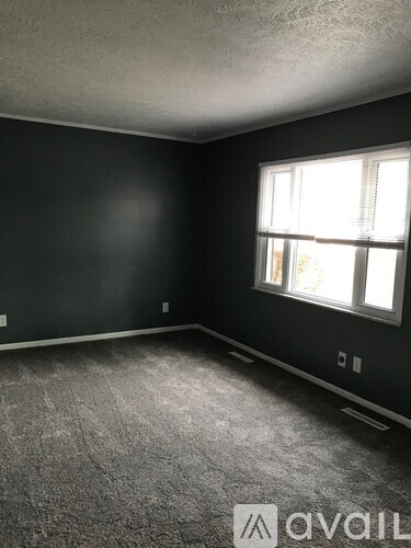 A room with a window and a carpeted floor.