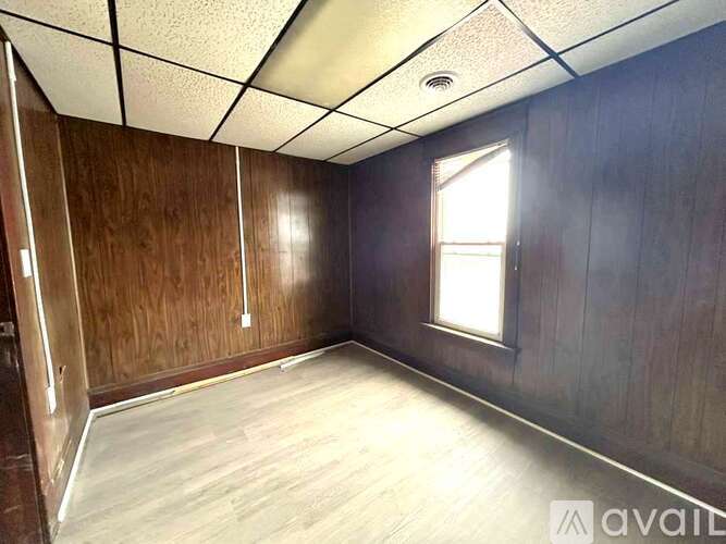 A room with wooden walls and a window on the right side.