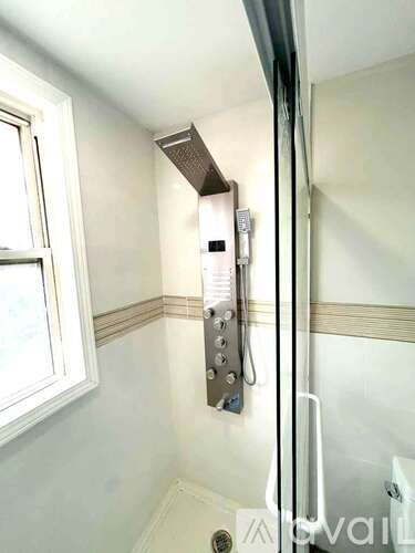 A bathroom with a glass shower door and a window.
