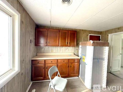 A kitchen with wooden cabinets and a white chair.