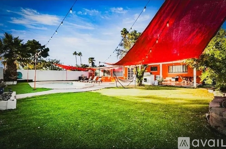 A red building with a white door and windows is surrounded by a green lawn.