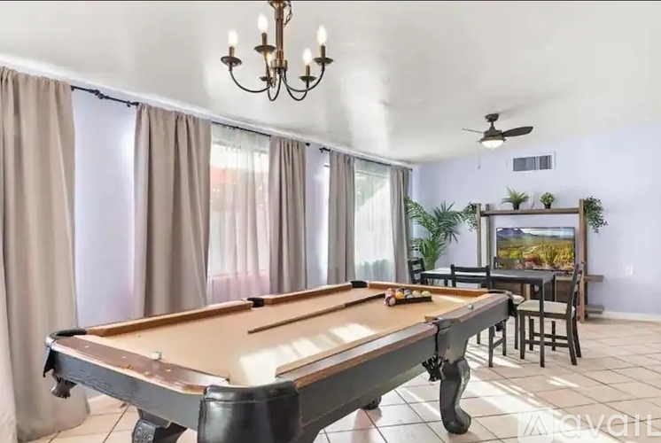 A pool table is in the middle of a room with a chandelier hanging from the ceiling.
