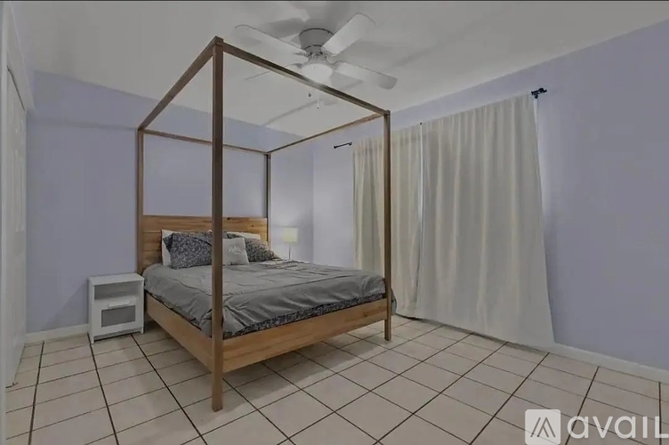 A bedroom with a four-poster bed and a ceiling fan.
