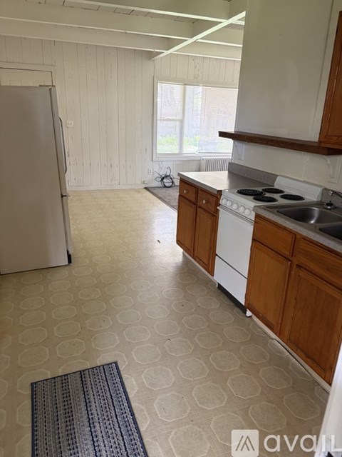 A kitchen with a white fridge, white stove, and wooden cabinets.