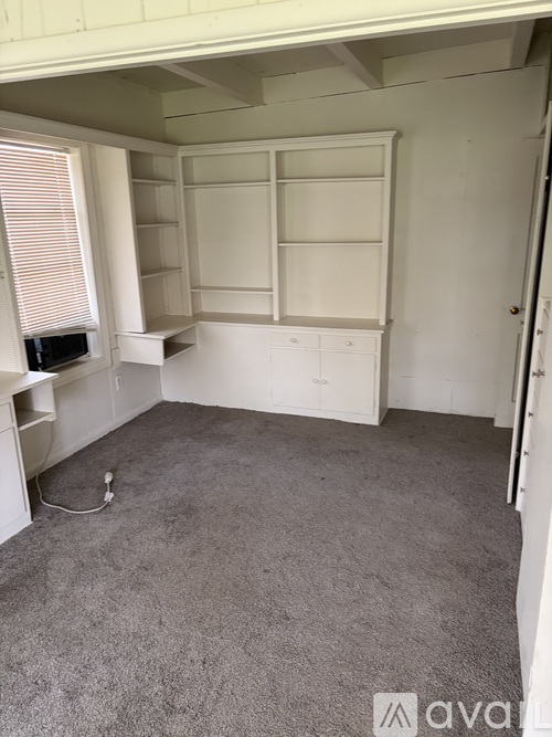 A room with a grey carpet and white furniture.