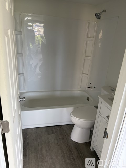A white bathroom with a toilet, sink, and bathtub.