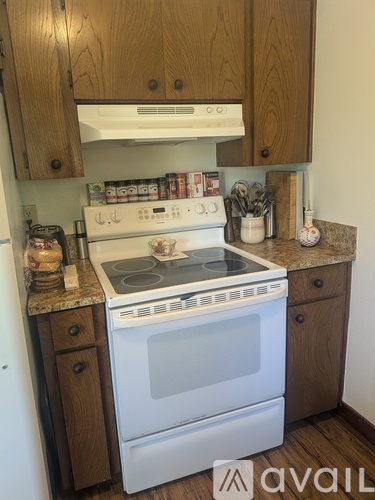 A white oven with a stove top sits under a cabinet in a kitchen.