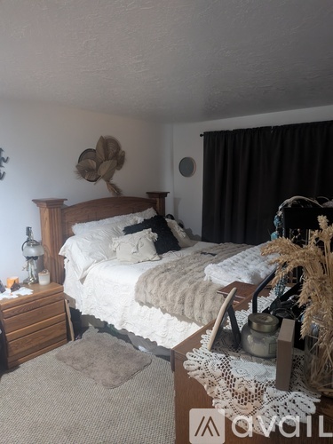 A bedroom with a bed, nightstand, and a hat on the wall.