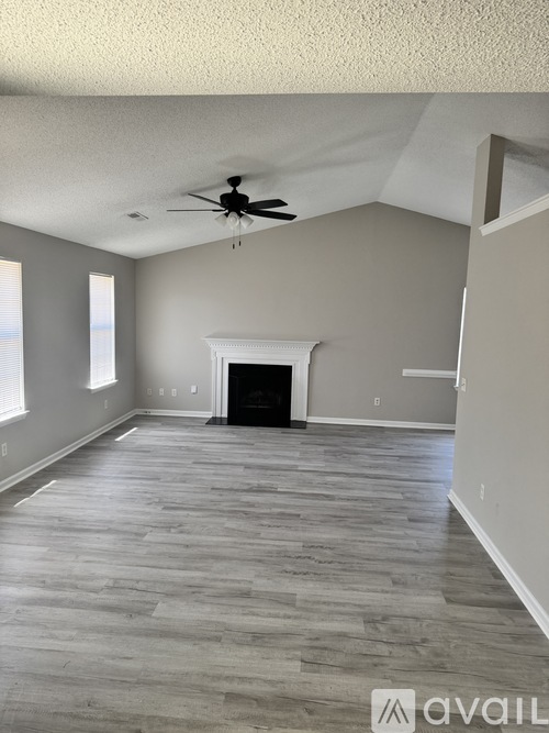 A spacious room with a fireplace and a ceiling fan.