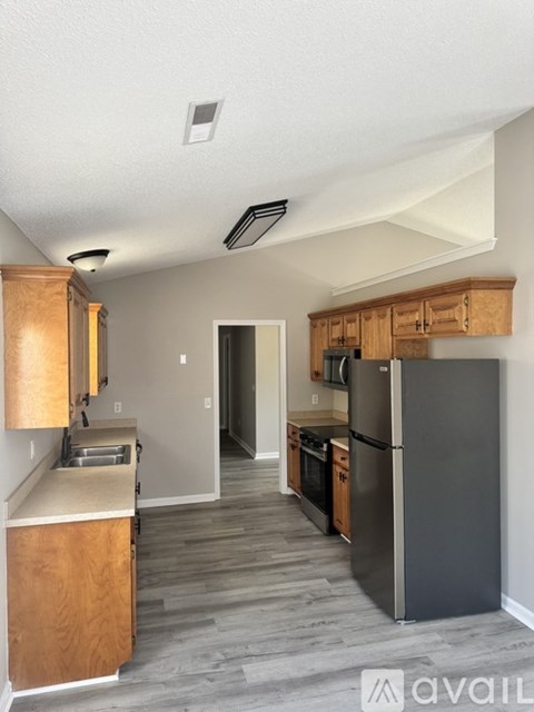 A kitchen with a refrigerator, sink, and cabinets.