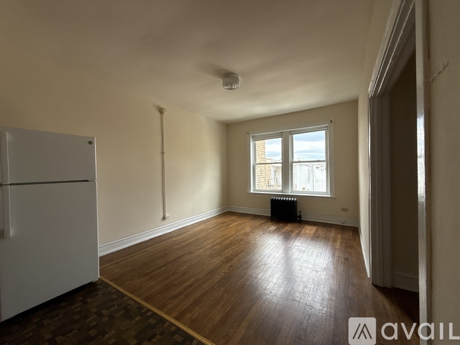A room with wooden floors and a window with a radiator beneath it.