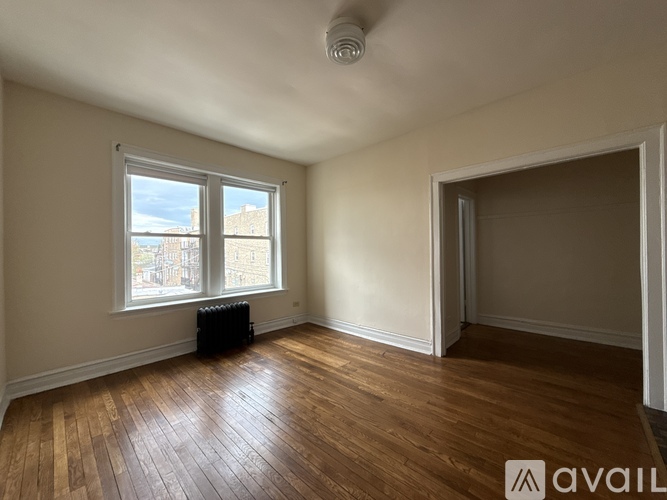 A room with wooden floors and a window overlooking a cityscape.