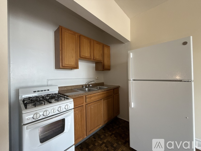 A kitchen with a white fridge, white stove and wooden cabinets.