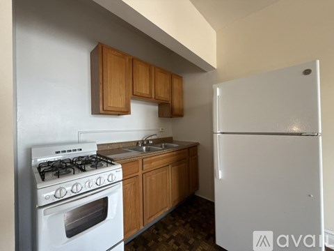 A kitchen with a white fridge, white stove and wooden cabinets.
