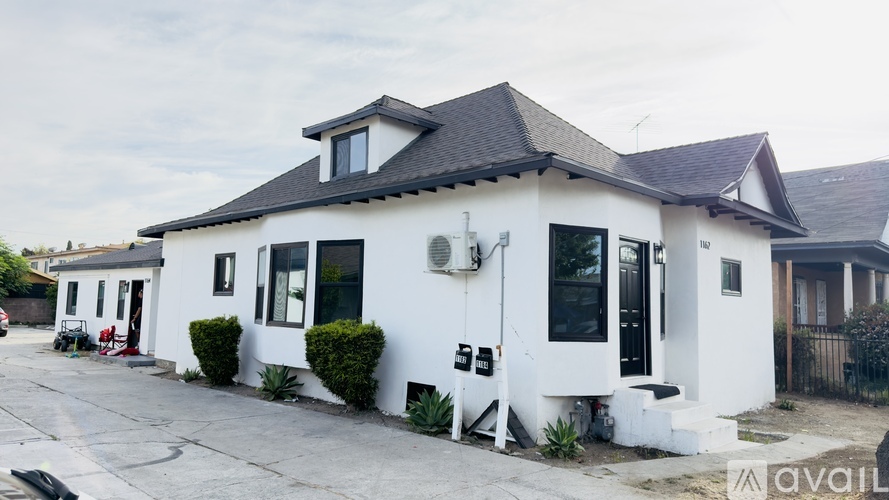 A white house with a black roof and a black fence.