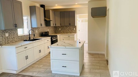 A kitchen with white cabinets and a tiled backsplash.