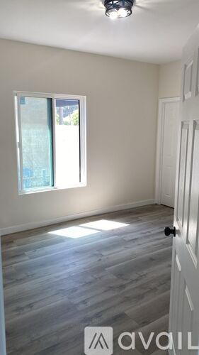 A room with a white door and a window with a view of a building outside.